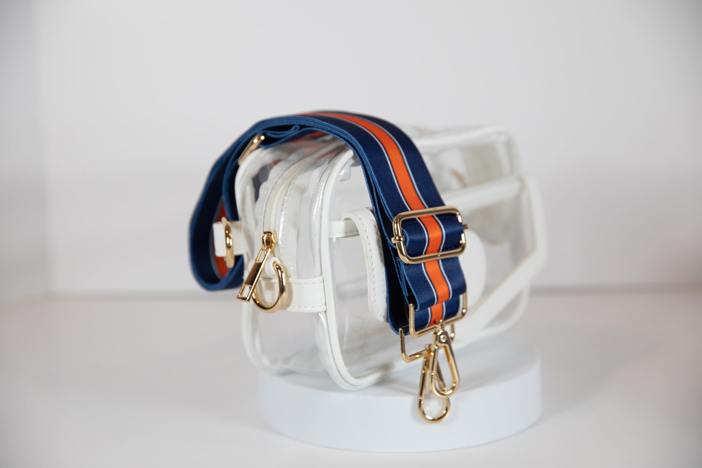 Clear stadium bag with white leather trim, side facing, with a crossbody strap in Denver Broncos colors.